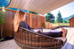 Doc-Holidays-Cabin-Deck-–-with-woman-sitting-in-outdoor-lounge-drinking-coffee-300x200.jpg